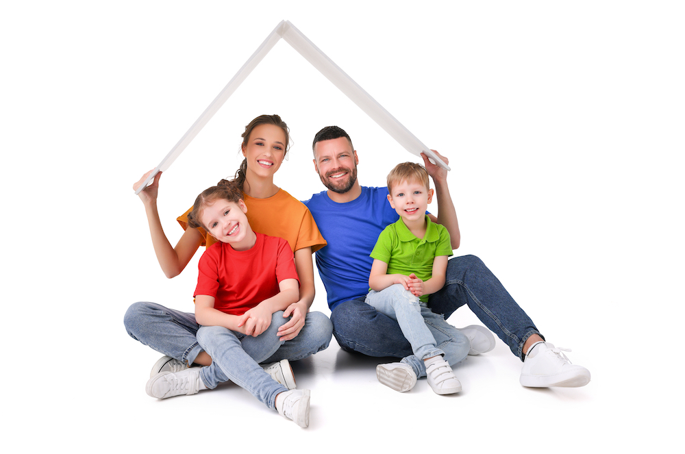 Delighted,Couple,With,Kids,Sitting,Under,Paper,Roof,In,Studio